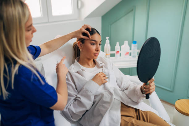 Skilled female plastic surgeon and dermatologist, doing the brow lift procedure on the young female client, while using the botox fillers, in her modern ordination